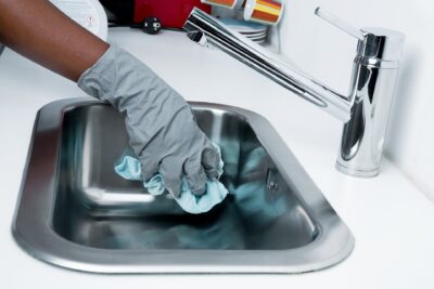 Image of person cleaning a sink wearing rubber gloves